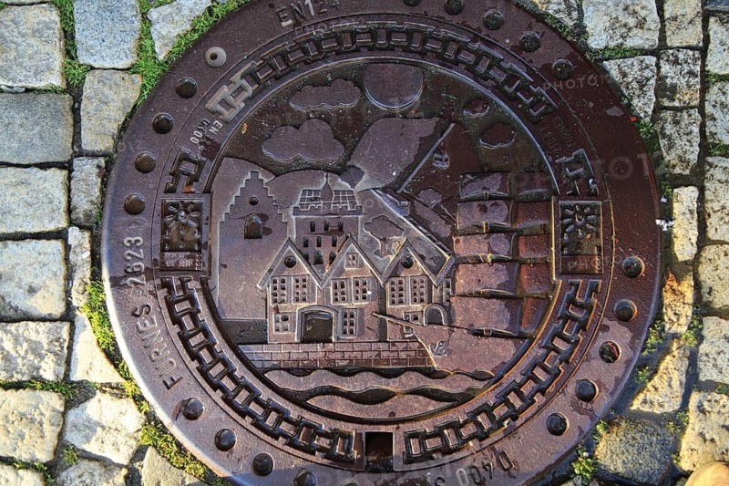 Looking down on old metal manhole cover city of Bergen, Norway, Europe