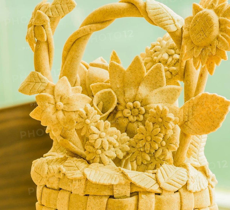 Handcrafted beige sculpture of a floral basket with detailed leaves, Teig, gebacken
