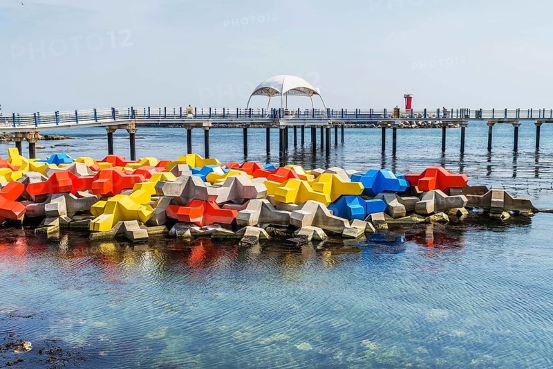 Large blocks of concrete in primary colors in water with boardwalk in background in Goseong, South Korea, Asia