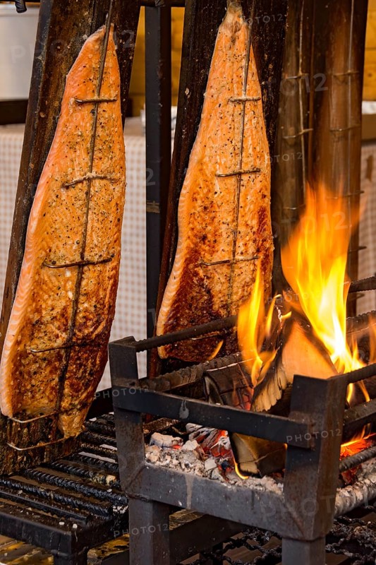 Flame-grilled salmon in a fire bowl, fillets of salmon grilled over an open flame, fish cooked, speciality from Finland, Leumulohi, snack bar, market stall, folk festival Kalter Markt, Kaale Määrt, funfair, fairground, Ortenberg, Wetterau, Hesse, Germany, Europe