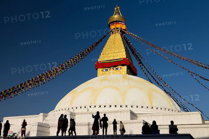People gathered at Bouddhanath, the Bouddha Stupa, on a sunny, spring afternoon. It is the largest stupa in Nepal, one of the World Heritage Site in the Kathmandu Valley, and a very important religious centre for the locals, Tibetan refugees and all the Buddhists. Bouddhanath has been reconstructed after the severe damages caused by the 2015 earthquake. Kathmandu Metropolitan City, Bagmati Province, Nepal, Asia