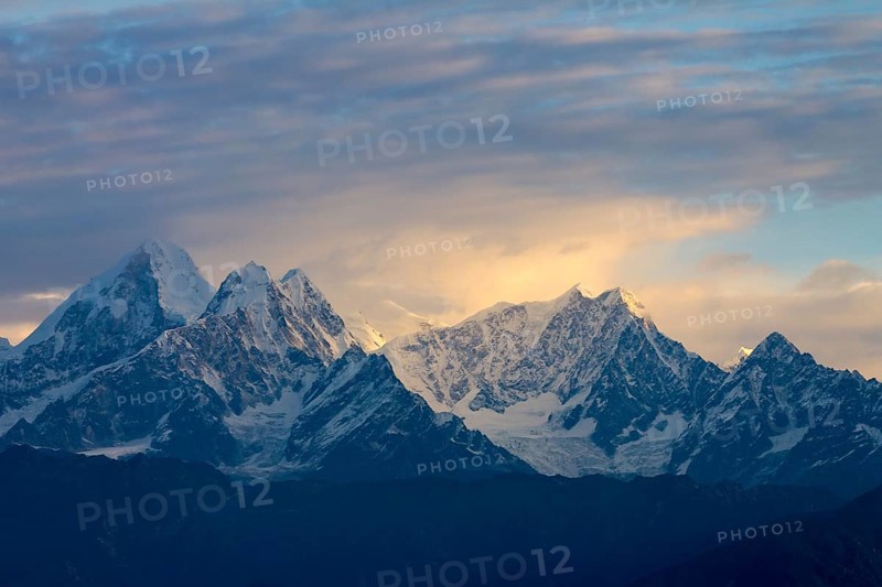 Langtang Himal, under the fairly cloudy sky, lit by the early-morning light, seen at sunrise on a late November day. Dorje Lhakpa is the most prominent mountain in this view (1st on the left-hand side) . The Himalayas. Photographed from Nagarkot, the popular viewpoint above Kathmandu Valley. Bhaktapur District, Bagmati Province, Nepal, Asia