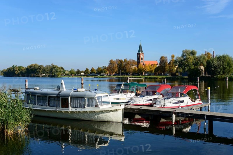 Boats lying on a calm lake in front of a church surrounded by trees under a clear blue sky, ships, harbour, church Maria Meeresstern, Werder, island, Havel, Brandenburg
