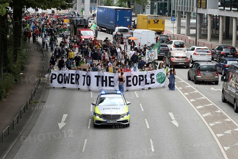 Police car and demonstrators behind banner with the inscription Power to the people at the alliance demo on climate racism and climate flight, with Fridays For Future, Extinction Rebellion, Sea-Watch, Sea-Eye, Seebrücke, Omas gegen Rechts in Hamburg, Germany, among others, Europe