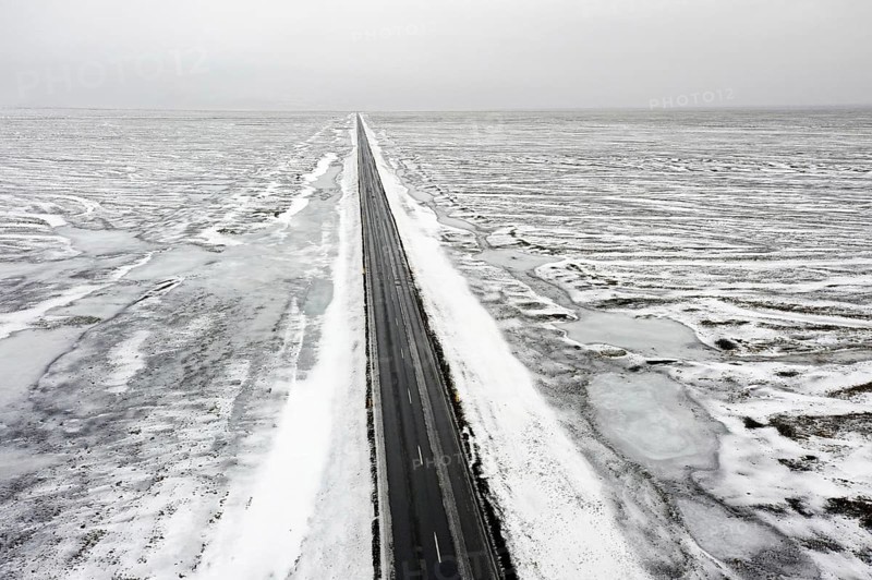 Aerial view over empty Route 1, Ring Road, two-lane national road in desolate snow covered winter landscape, Suðurland, Southern Region, Iceland, Europe