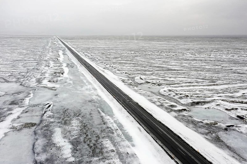 Aerial view over empty Route 1, Ring Road, two-lane national road in desolate snow covered winter landscape, Suðurland, Southern Region, Iceland, Europe