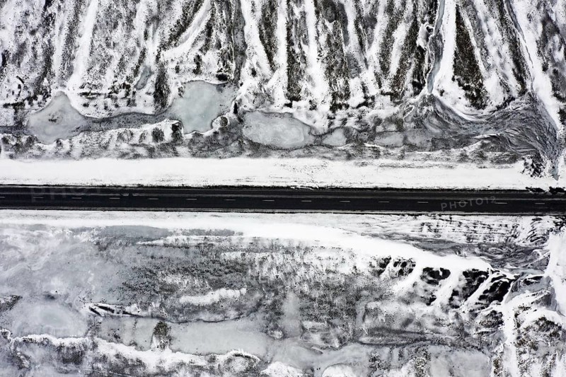 Aerial view over empty Route 1, Ring Road, two-lane national road in desolate snow covered winter landscape, Suðurland, Southern Region, Iceland, Europe