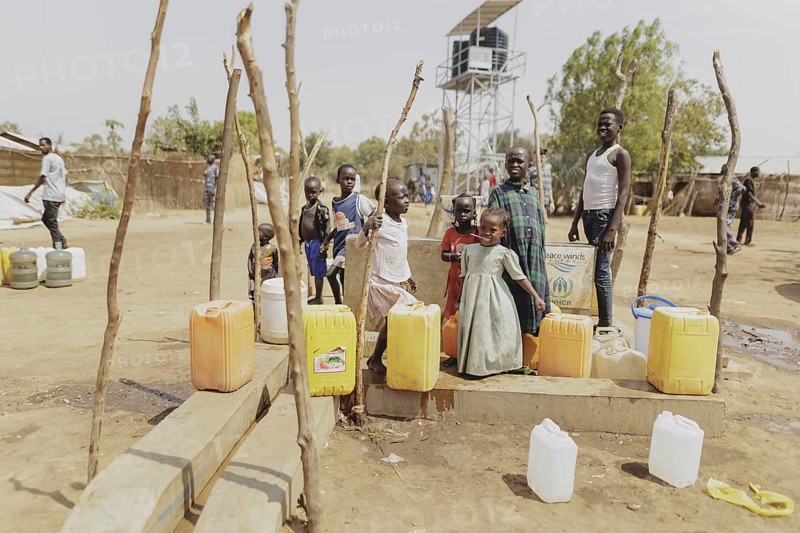Children and adults stand with water canisters at a well in the Gorom refugee settlement southwest of Juba, 26 Jan. 2024 / Photographed on behalf of the Federal Foreign Office