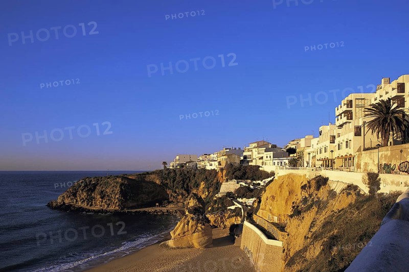 Apartments in early morning light under a deep blue sky overlook the deserted west end of the main beach at Albufeira, Algarve, Portugal, Europe