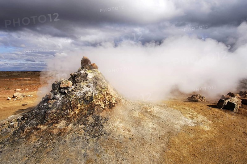Close-up of steaming vent or fumarole in a geothermal landscape with a view of distant hills at Hverarond near Myvatn, north Iceland