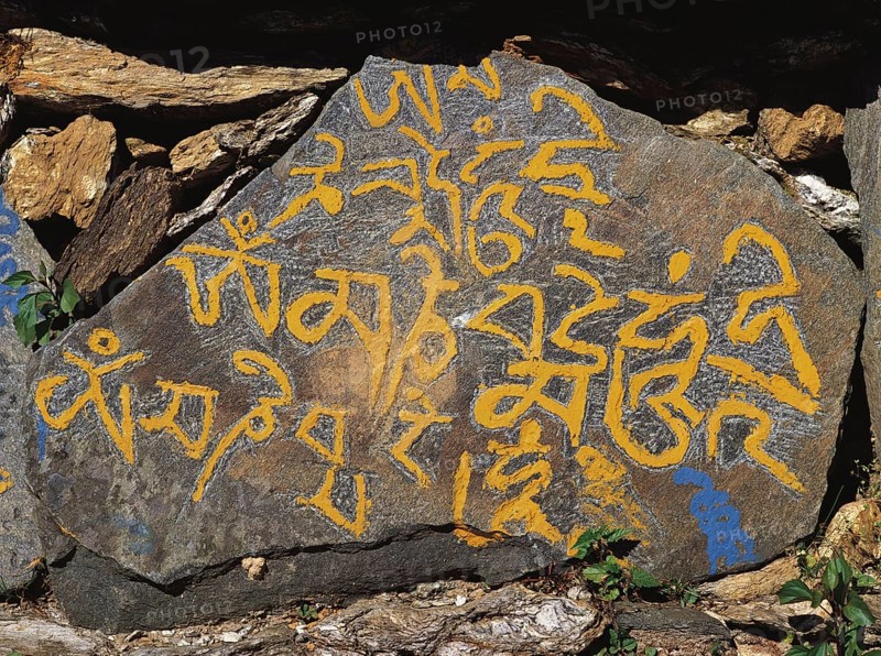 Carved mane-stone carrying the Buddhist message Om mane Padme hom by the side of a trail in east Nepal