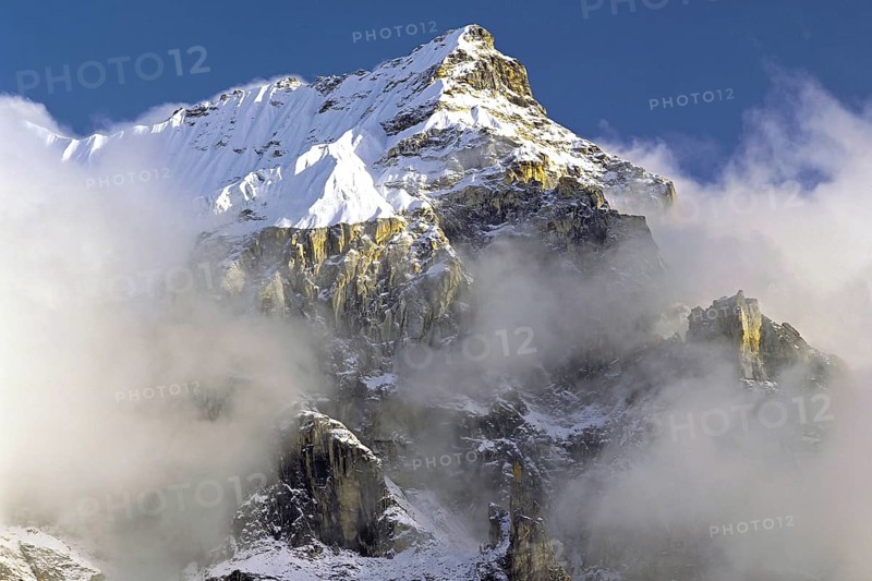 Afternoon mist and clouds gather around the dramatic crags and summit of an un-named peak in the Kangchenjunga region of east Nepal