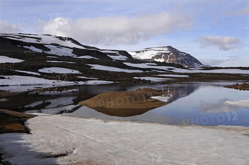 Still partly-frozen meltwater pool and the mountain Bjolfur in the Fjardarheidi range near Seydisfjordur, east Iceland