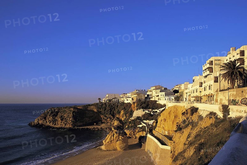 Apartments in early morning light under a deep blue sky overlook the deserted west end of the main beach at Albufeira, Algarve, Portugal, Europe
