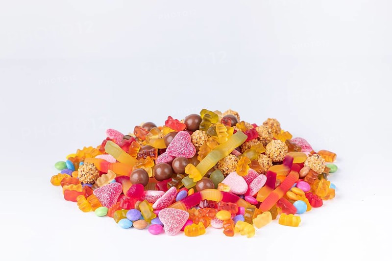 A colourful pile of different sweets on a white background, copy room
