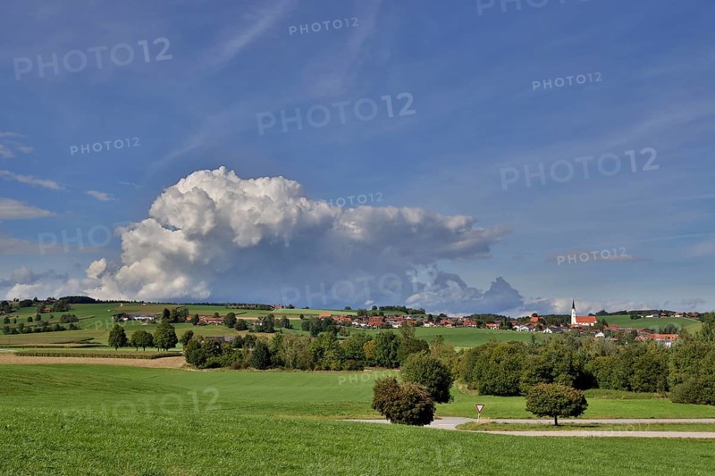 Threatening thundercloud over a sunny, hilly landscape with a village in the foothills of the Alps, Kirchdorf near Haag, Upper Bavaria, Bavaria, Germany, Europe