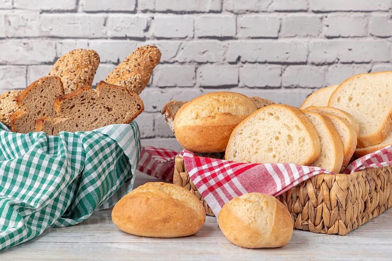 Fresh pastries and bread in two baskets in front of a brick wall