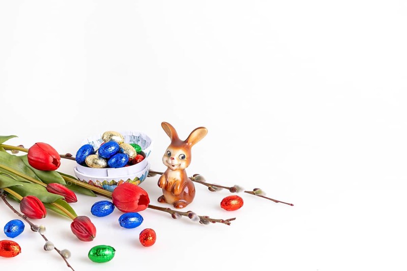 Easter composition with an Easter bunny and a bowl full of chocolate eggs, white background, copy space