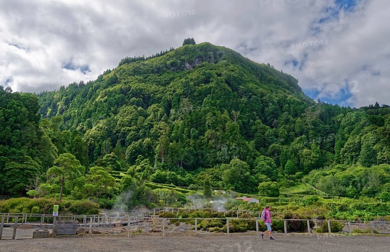 Tourists visit an area of volcanic activity surrounded by green mountains and plumes of steam, Fumarolas Lagoa das Furnas, Furnas, Sao Miguel, Azores, Portugal, Europe