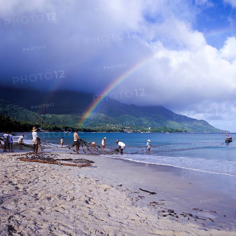 Seychelles, Mahe, Beau Vallon, fishermen pull fishing net ashore, Africa