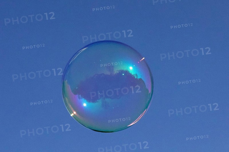Soap bubbles coloured film of soapy water with reflection in front of blue sky