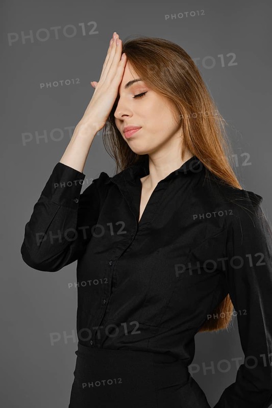Upset woman makes facepalm gesture, slapping herself on the forehead with the palm of her hand