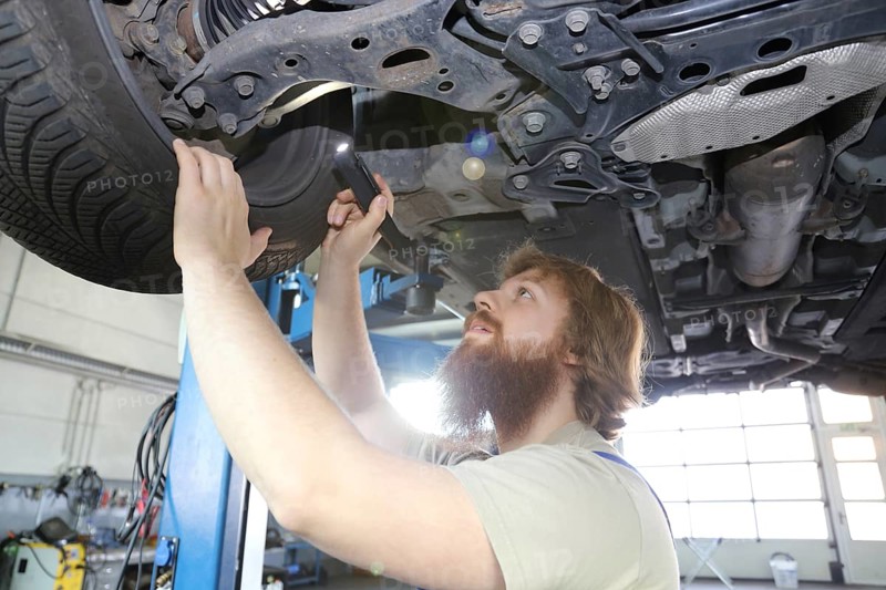 Symbolic image: Motor vehicle mechatronics technician inspects a car on the lift
