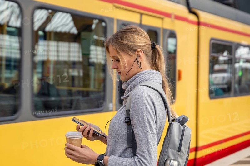 Close-up of a young woman in front of a train at the station