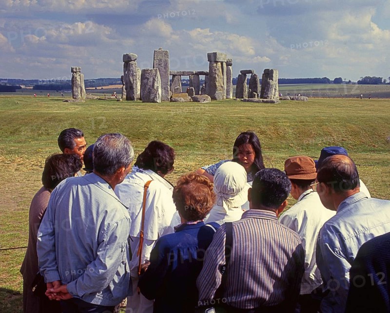 Group of Japanese tourists with guide visiting Stonehenge monument at Salisbury, England, UK, Europe. Scanned 6x6 slide