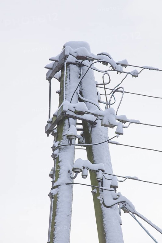 Old, snow-covered telegraph pole in winter, Germany, Europe