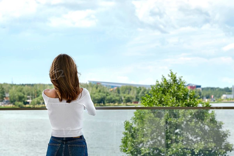 Back view of woman standing on the observation deck and enjoying amazing view of the city river