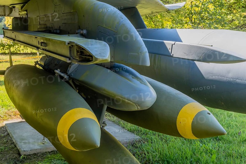 Closeup battery of bombs mounted on port side wing of jet fighter on display in public park