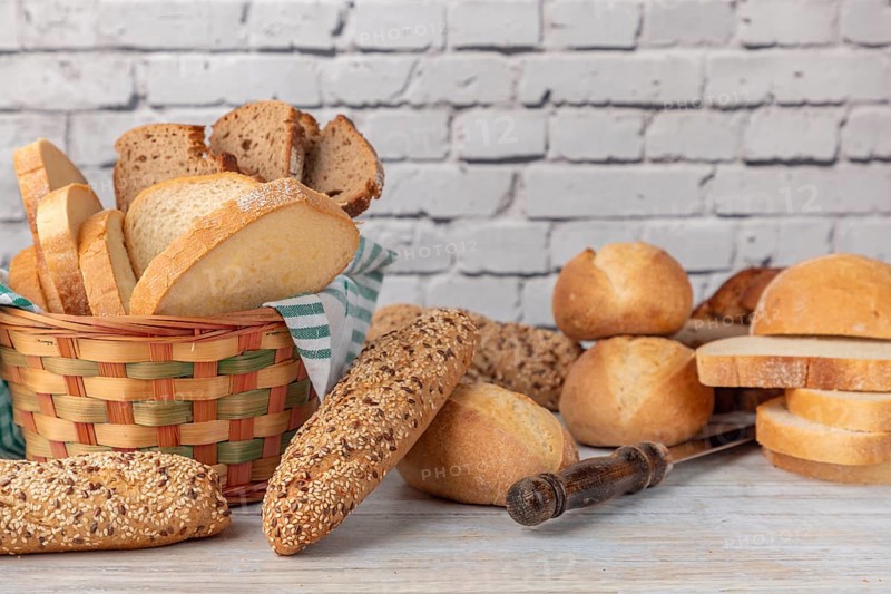 Various wholemeal and white breads in a bread basket on a country-style worktop
