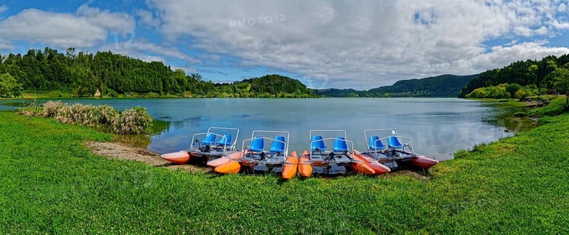 Tranquil Furnas Lake with pedal boats on the shore, surrounded by green nature and a cloudy sky, Furnas Lake, Furnas, Sao Miguel, Azores, Portugal, Europe
