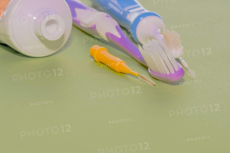 Closeup of toothbrushes and flossing picks next to opened tube of toothpaste