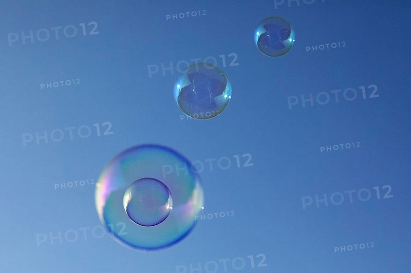 Soap bubbles four coloured film of soapy water on top of each other in front of a blue sky