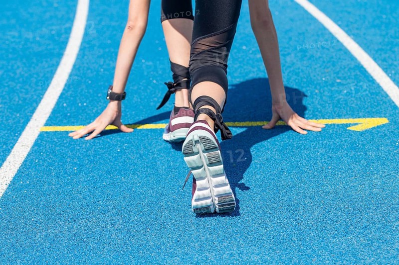 Athletics symbol: Young woman in front of the start of a race