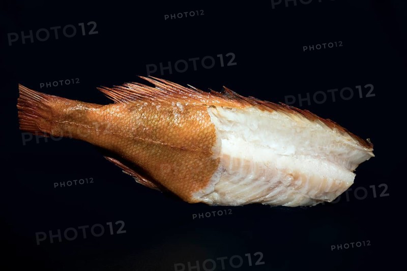 Smoked redfish without head, with half of the skin removed and part of the back fillet cut out, food photography with black background