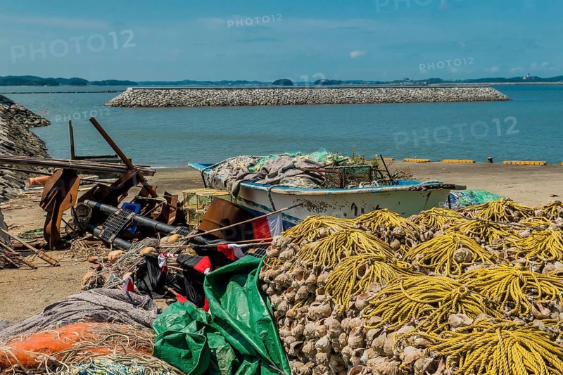 Small fishing boat filled with nets and gear beached among assortment of fishing paraphernalia in Yeosu, South Korea, Asia