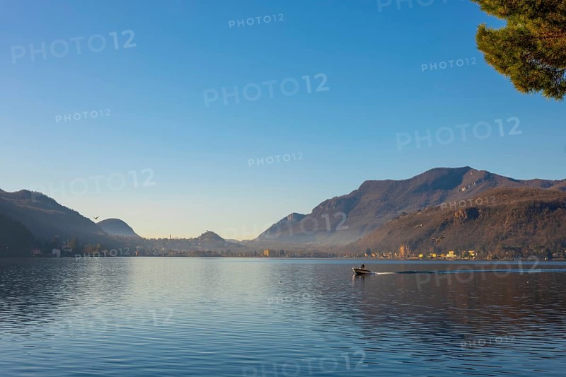 Boat Travel on Lake Lugano with Mountain and City in a Sunny Day with Clear Sky in Porto Ceresio, Lombardy, Italy, Europe