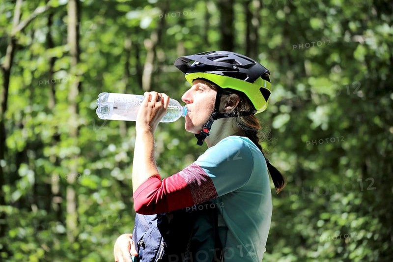 Symbolic image for drinking enough during sport: mountain biker quenches her thirst