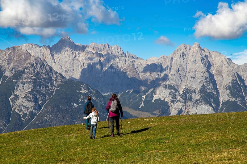 Hiking with children in Seefeld, Tyrol: Family hiking across an alpine meadow, with the Wetterstein mountains in the background
