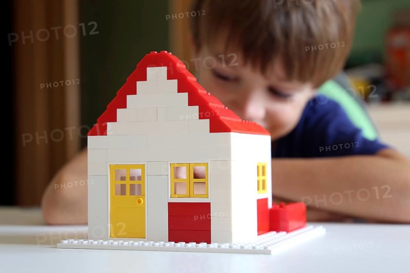 Symbolic image: Boy builds a house with building blocks