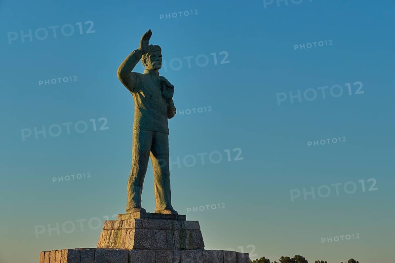 Statue of a man with his arm outstretched towards the sky at dawn, bronze statue of a waving sailor in memory of the souls lost at sea, Gythio, Mani, Peloponnese, Greece, Europe