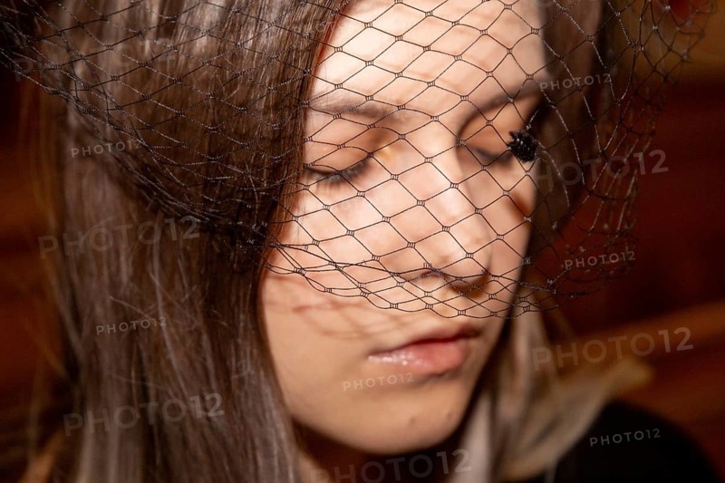 Close-up of a grieving young woman with a mourning veil in church (symbolic image)