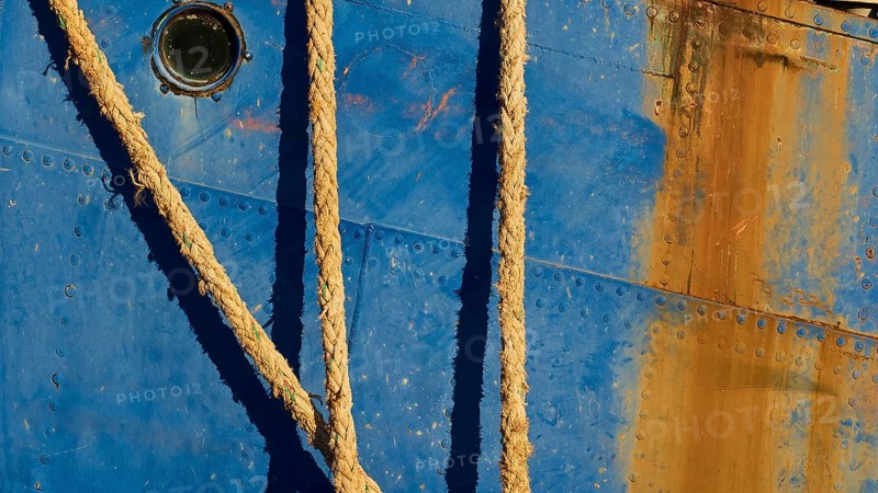 Detailed view of the side of a blue ship with ropes and rusty patches, Gythio, Mani, Peloponnese, Greece, Europe