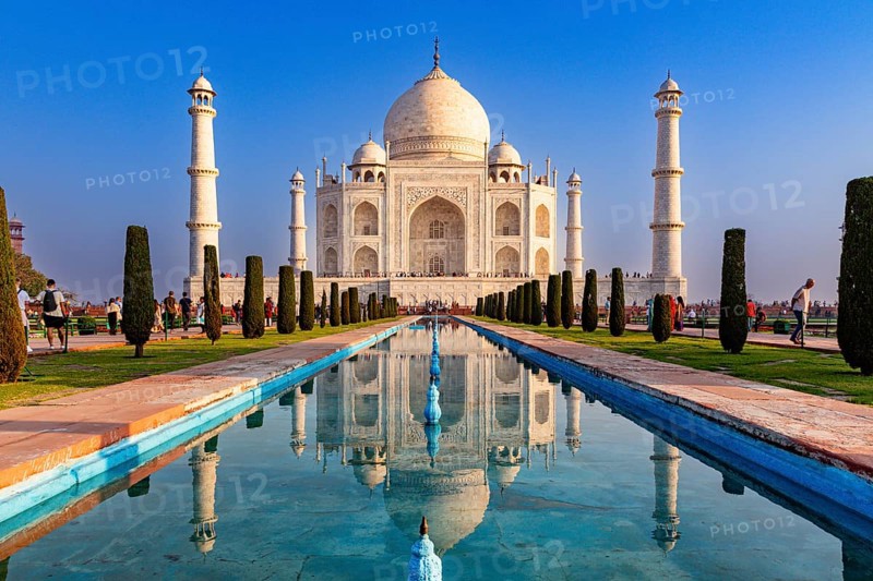 The sublime Taj Mahal is reflected in a long pool of water under a blue sky, Taj Mahal, Agra, India, Asia