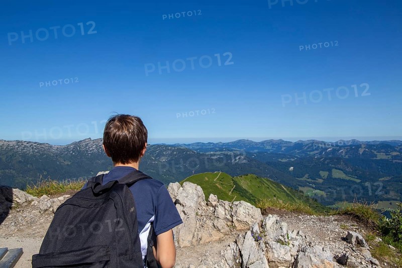 Hiking in the Allgaeu Alps: A young boy looks out over the Alpine foothills from the summit of the Kanzelwand, 2059 metres above sea level