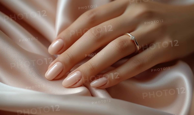 A woman's hand with a pink manicure and diamond ring on a lustrous silk fabric AI generated