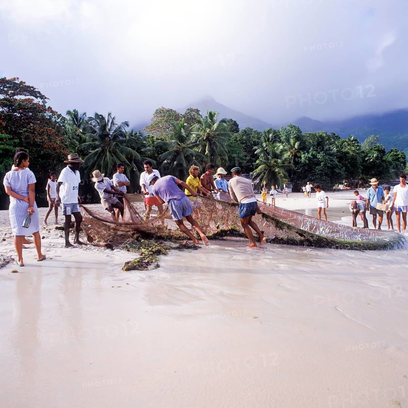 Seychelles, Mahe, Beau Vallon, fishermen pull fishing net ashore, Africa